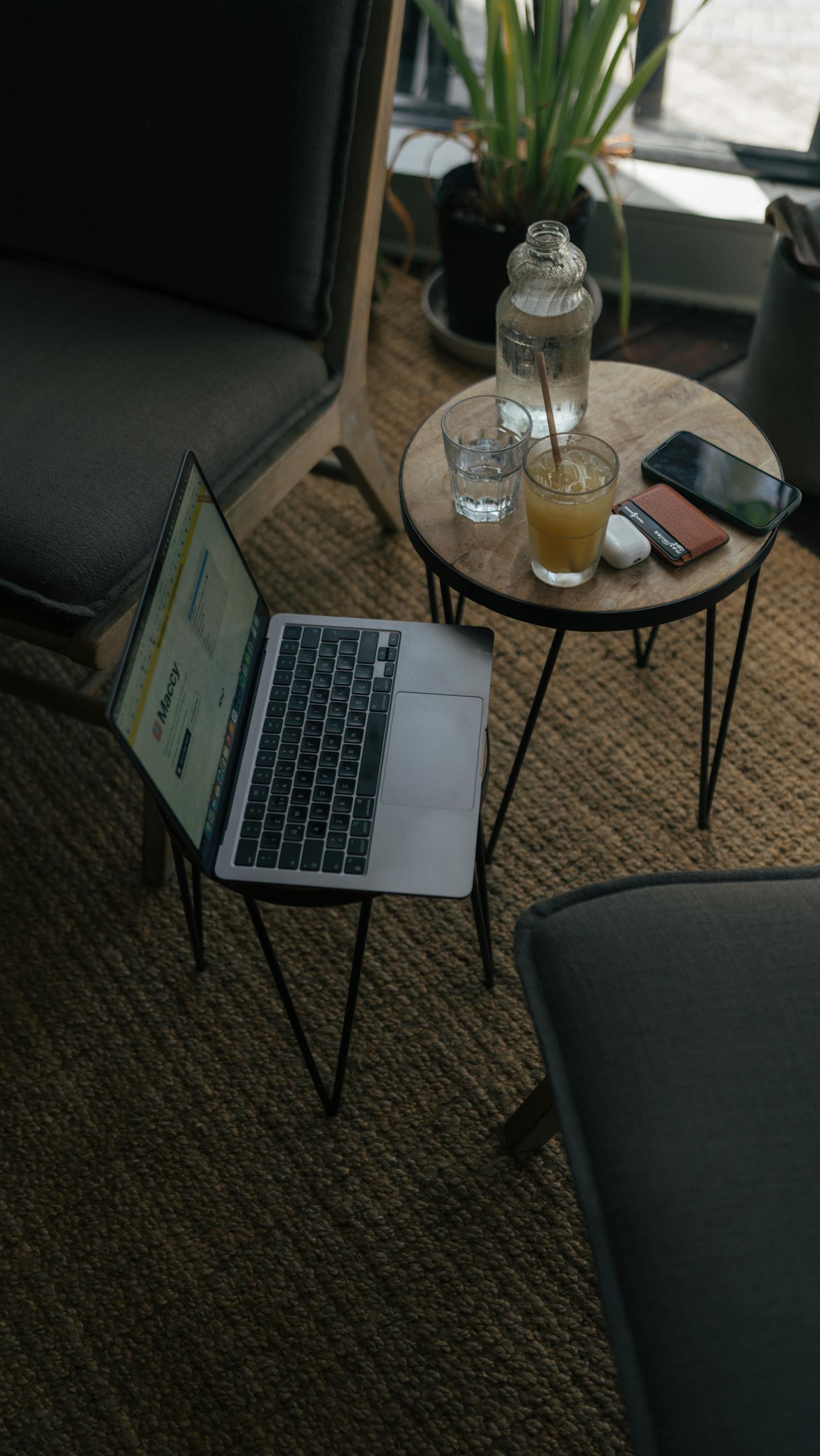 A cozy indoor workspace featuring a laptop, drinks, and smartphone on a table.