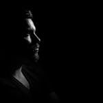 Profile portrait of a man in black and white, emphasizing shadows and highlights.